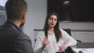 Genç, kendine güvenen bayan patron ofisteki meslektaşıyla konuşuyor, detayları anlatıyor, şirket geliştirme planını tartışıyor.