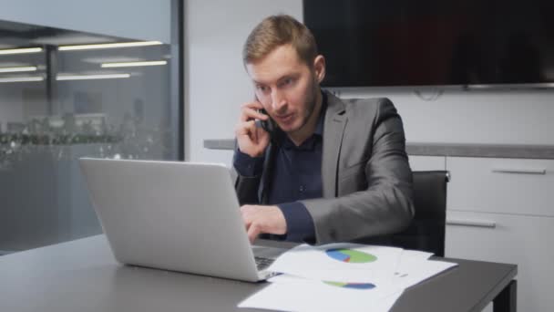 Online raadplegingsconcept. Jonge drukke man manager bespreekt project grafieken met partner op mobiele telefoon op kantoor — Stockvideo
