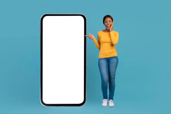 Överraskad ung svart kvinnlig pekande på Big Blank Smartphone med blankskärm — Stockfoto