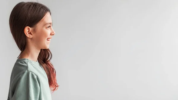 Perfil retrato de menina sorrindo olhando para o lado em fundo cinza — Fotografia de Stock