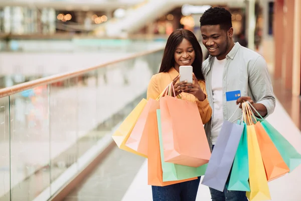 Portrait of happy black couple using smartphone holding credit card — Stock Photo, Image