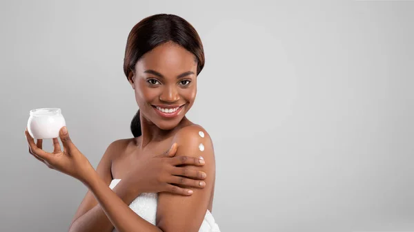 Conceito Nutritivo da Pele. Linda senhora afro-americana aplicando creme hidratante para o corpo — Fotografia de Stock