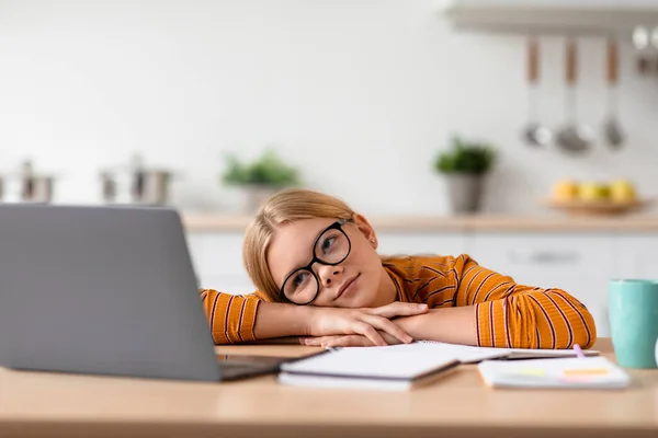 Cansado bonito europeu adolescente loira menina em óculos colocar a cabeça na mesa assistir vídeo lição no laptop — Fotografia de Stock