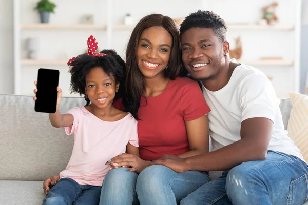 Vrolijk Afrikaans Amerikaans gezin van drie tonen blanco smartphone met zwart scherm — Stockfoto