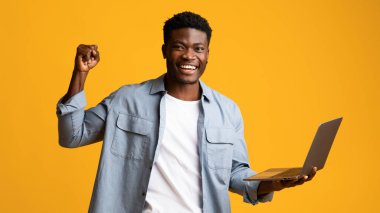 Mutlu Afro-Amerikan adam dizüstü bilgisayar tutuyor ve işaret ediyor.