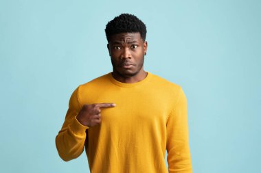 Kafası karışmış genç siyah adam kendini işaret ediyor.