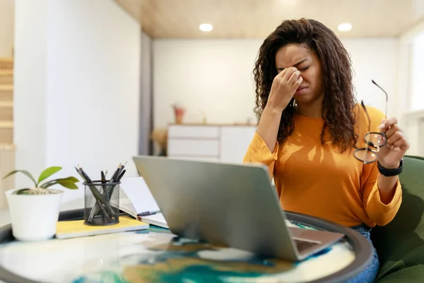 Уставшая чернокожая работница сидит за столом с компьютером — стоковое фото