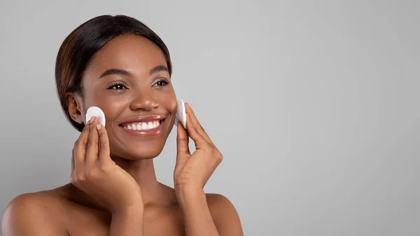 Cuidado de la piel. Sonriente hermosa piel de limpieza femenina negra con dos almohadillas de algodón —  Fotos de Stock