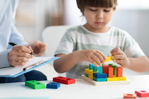 Schattig jongetje tijdens speeltherapie bij kinderpsychologen kantoor, professionele vrouw met notities maken — Stockfoto