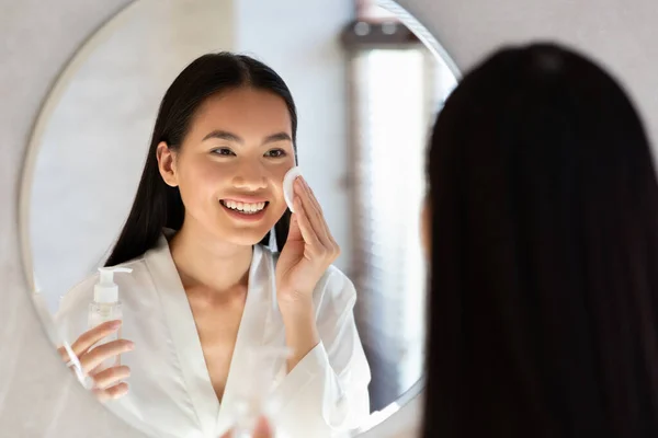 Attractive asian lady using cleansing milk, removing makeup — Stock Photo, Image