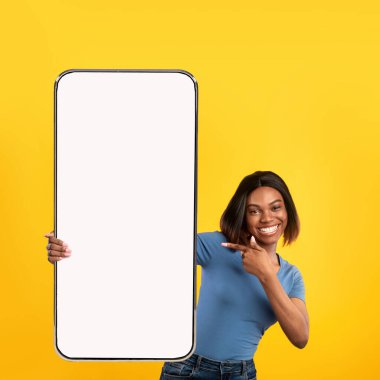 Heyecanlı siyah kadın beyaz, boş akıllı telefon ekranını işaret ediyor.