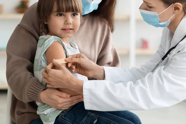 Mujer doctora poniendo yeso médico al brazo de los pacientes del niño después de la inyección de vacunación contra covid-19 durante pandemia —  Fotos de Stock