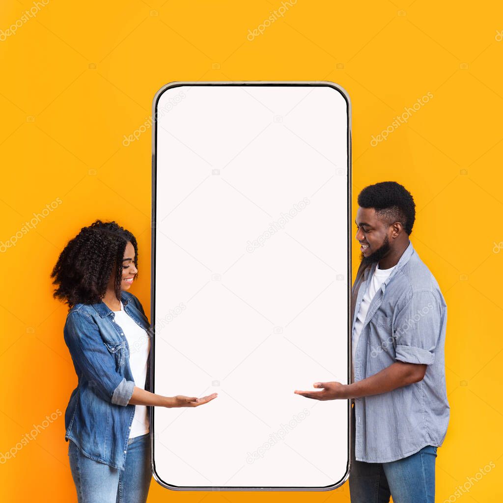 Excited black couple showing white empty smartphone screen