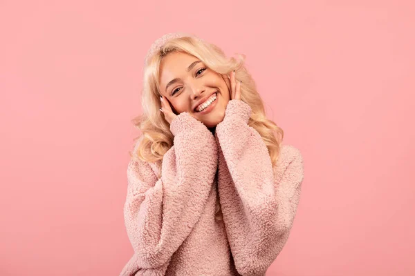 Porträtt av söt blond dam vidröra kinder i spänning, stående nöjd och ler mot kameran, rosa bakgrund — Stockfoto