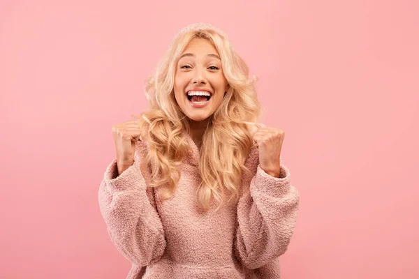 Ενθουσιασμένη ξανθιά γυναίκα που γοητεύει ΝΑΙ, γιορτάζει την επιτυχία ή τα επιτεύγματά της, αισθάνεται ενθουσιασμένη με το ροζ φόντο του στούντιο — Φωτογραφία Αρχείου