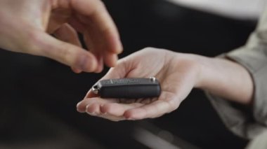 Araba paylaşım konsepti. Kadın elinin ofisteki tanınmayan adama araba anahtarı verirken yakın plan fotoğrafı.