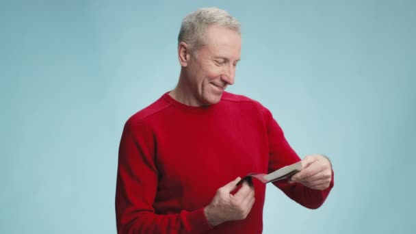 Счастливый пожилой человек, читающий информацию о рейсах, показывающий билеты на самолет и паспорт на камеру, наслаждающийся отпуском — стоковое видео