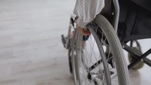 Styl życia dla niepełnosprawnych. Nierozpoznawalna kobieta jeżdżąca na wózku inwalidzkim w domu, poruszająca się do przodu, śledząca strzał, wolna przestrzeń — Wideo stockowe