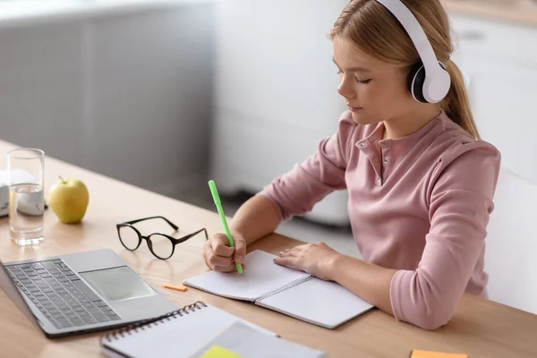 Serious busy cute european adolescent blonde girl in headphones study at home with laptop do homework — Stock Photo, Image