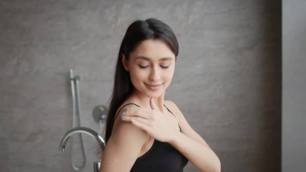 Happy Woman Applying Body Cream On Shoulders Moisturizing Skin Indoors — Stock Video