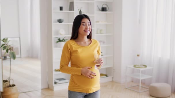 Hydratatie van het lichaam. jong zwanger aziatische vrouw drinken water uit glas thuis — Stockvideo