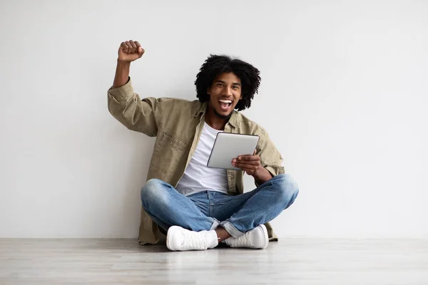 Νίκη στο διαδίκτυο. Χαρούμενο μαύρο αρσενικό γιορτάζει την επιτυχία με ψηφιακή ταμπλέτα — Φωτογραφία Αρχείου