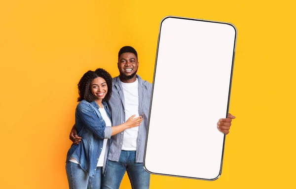 Emocionado casal preto mostrando branco tela do smartphone vazio — Fotografia de Stock