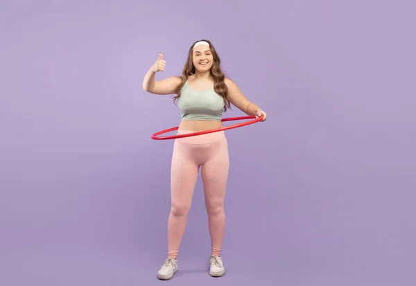Satisfecho joven caucásico más tamaño señora atleta en ropa deportiva con hula aro mostrar pulgar hacia arriba —  Fotos de Stock
