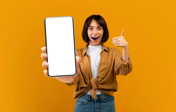Pretty millennial woman holding smartphone with empty screen and gesturing — Stock Photo, Image