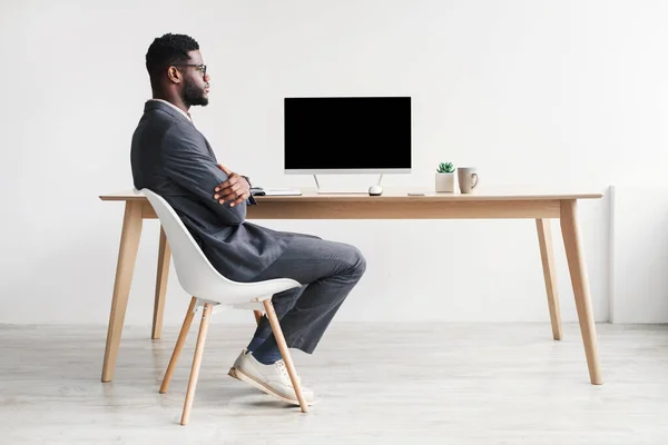 Πλήρες μήκος του νεαρού μαύρου επιχειρηματία στο γραφείο φορούν χρησιμοποιώντας υπολογιστή με mockup για το σχεδιασμό ιστοσελίδα κατά λευκό τοίχο — Φωτογραφία Αρχείου