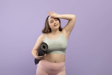 Yorgun, genç Avrupalı ve spor kıyafetleri giyen bir kadın antrenman sonrası terler ve boş alanlara bakar.