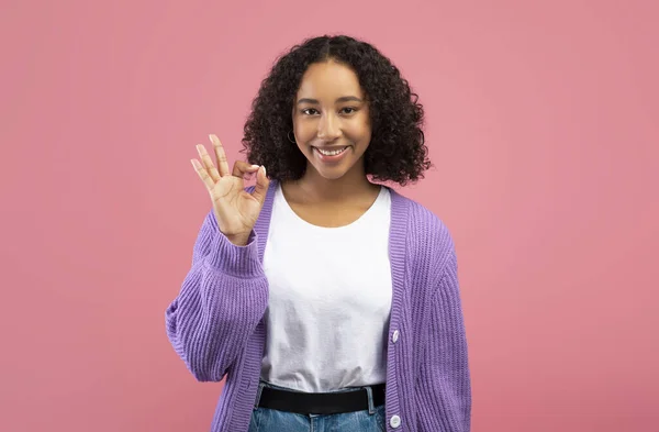 Sonriendo joven mujer afroamericana mostrando gesto bien, aprobando o recomendando algo sobre fondo rosa — Foto de Stock