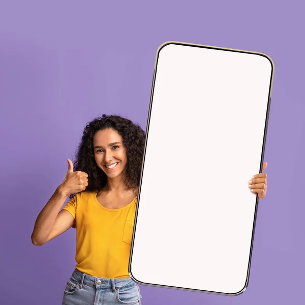 Recomendación. Retrato de mujer feliz sosteniendo un gran teléfono inteligente con pantalla en blanco y haciendo gesto de pulgar hacia arriba, maqueta —  Fotos de Stock