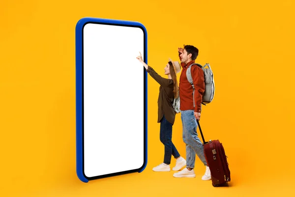 Pareja de turistas usando la pantalla vacía que toca enorme del teléfono, fondo amarillo — Foto de Stock