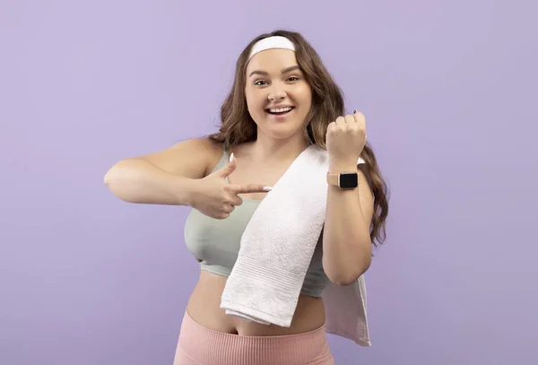 Šťastný tisíciletý běloch plus velikost dáma ve sportovním oblečení s ručníkem show prst na fitness tracker — Stock fotografie