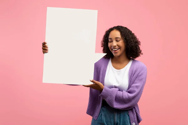 Joven mujer afroamericana alegre sosteniendo la burbuja del discurso en blanco con la maqueta para el diseño del anuncio en fondo rosa del estudio — Foto de Stock