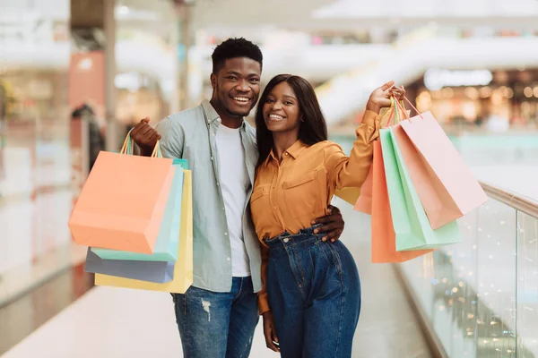 Beautiful black couple holding shopping bags looking at camera — Stock Photo, Image
