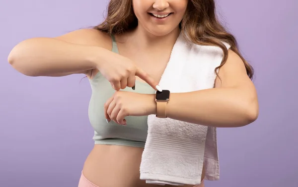 Gescheurde glimlach jonge Europese plus size dame in sportkleding controleert pols op fitness tracker — Stockfoto
