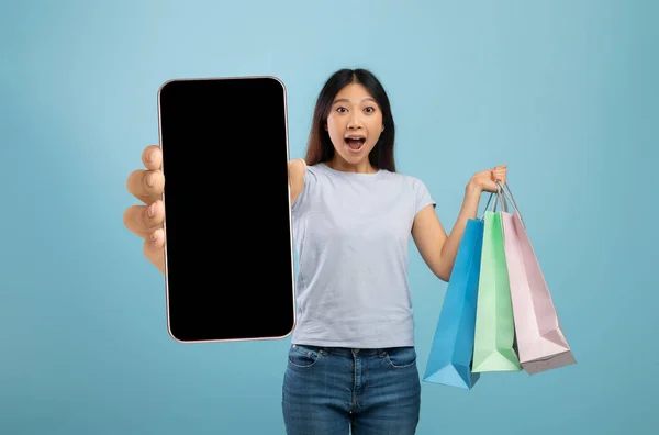 Signora emotiva che tiene borse della spesa e smartphone con schermo vuoto — Foto Stock