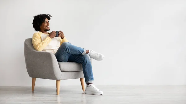 Boldog fiatal afro-amerikai srác pihentető székben egy csésze kávé — Stock Fotó