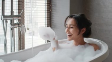 Banyoda köpüklü banyo yapan mutlu bayan.