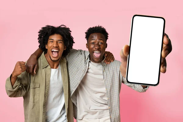 Überglücklich zwei schwarze männliche Freunde zeigen Handy mit weißem leeren Bildschirm und schreien vor Aufregung, Attrappe — Stockfoto