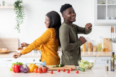 Neşeli siyah eşler birlikte yemek pişirirken mutfakta eğleniyorlar.