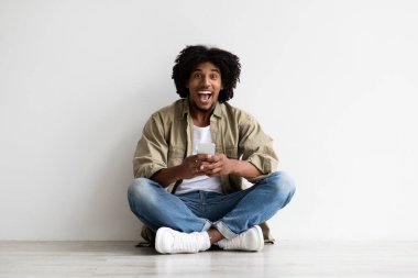 İnternetten satış. Heyecanlı mutlu zenci adam akıllı telefonu tutuyor ve kameraya bakıyor.