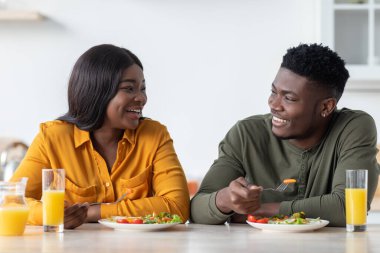 Romantik Afro-Amerikan çifti evde, mutfakta lezzetli bir kahvaltı yapıyorlar.