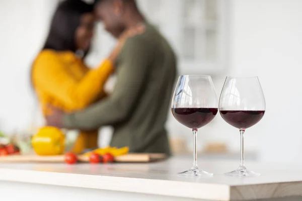 Foco seletivo em dois copos de vinho com casal preto romântico no fundo — Fotografia de Stock