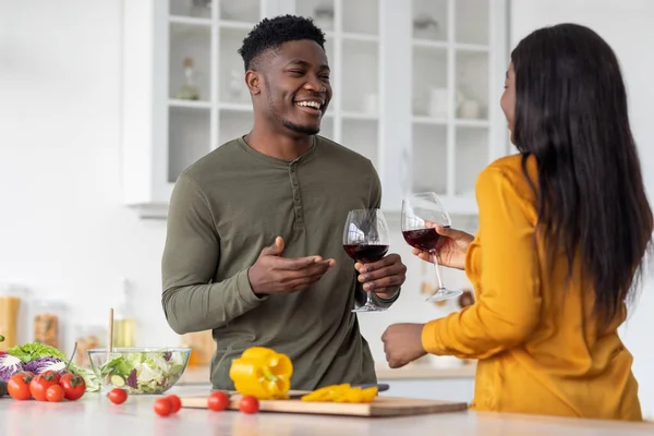 Bebida de aperitivo. alegre negro hombre y mujer bebiendo vino tinto en cocina — Foto de Stock