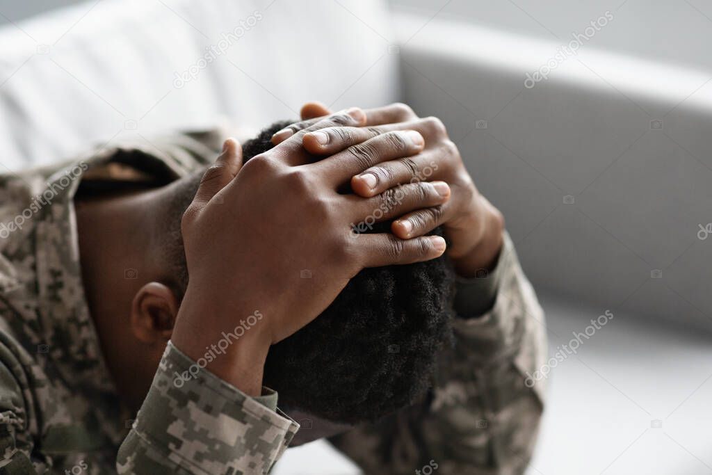 Unrecognizable military black man covering his head with palms
