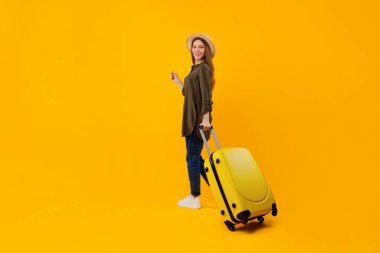 Sarı Stüdyo Arkaplanının Üzerinde Poz Veren Çantalı Turist Kadın