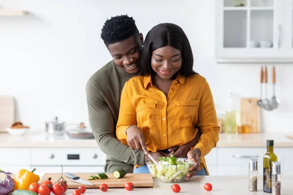 Romántico negro chico abrazando novia mientras ellos cocinar almuerzo juntos en cocina, — Foto de Stock